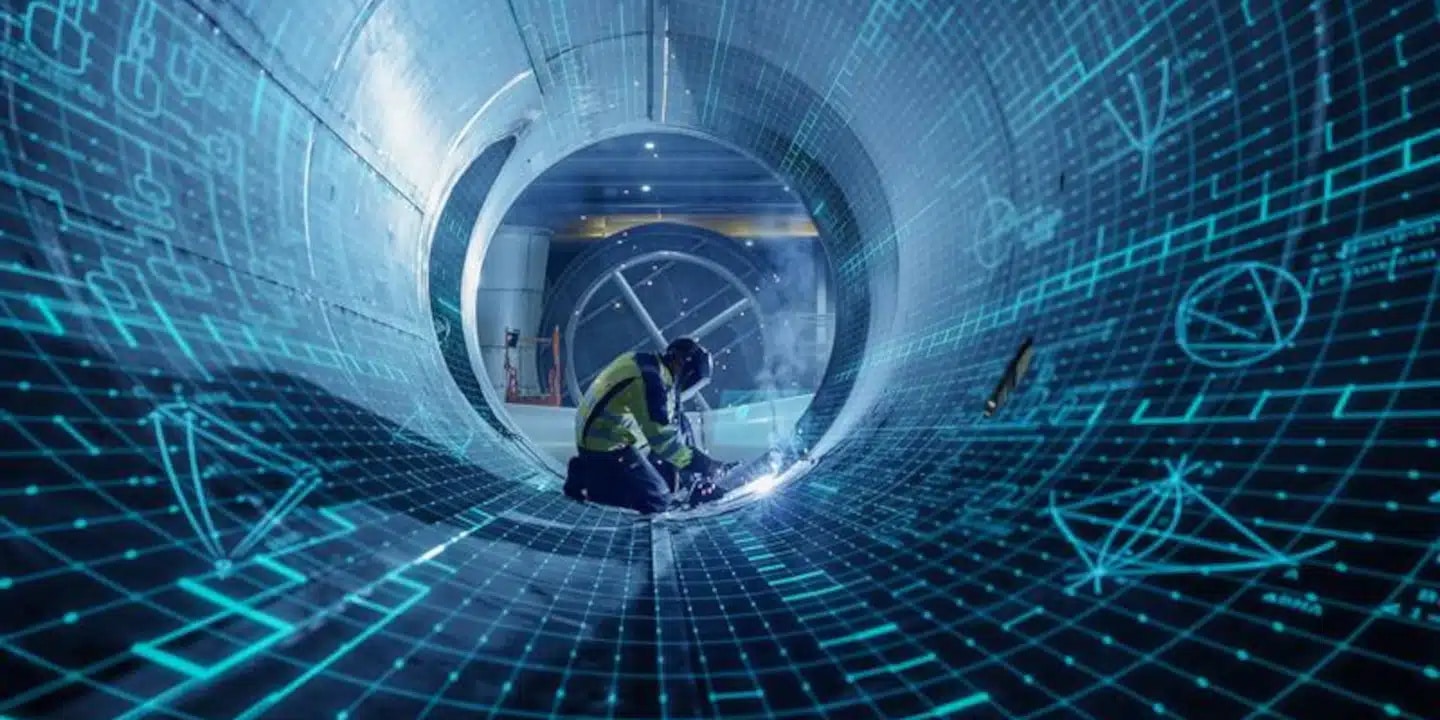 Worker in safety gear welds inside a large metal pipe, with blue digital graphics overlaying the interior to suggest advanced technology or engineering design.